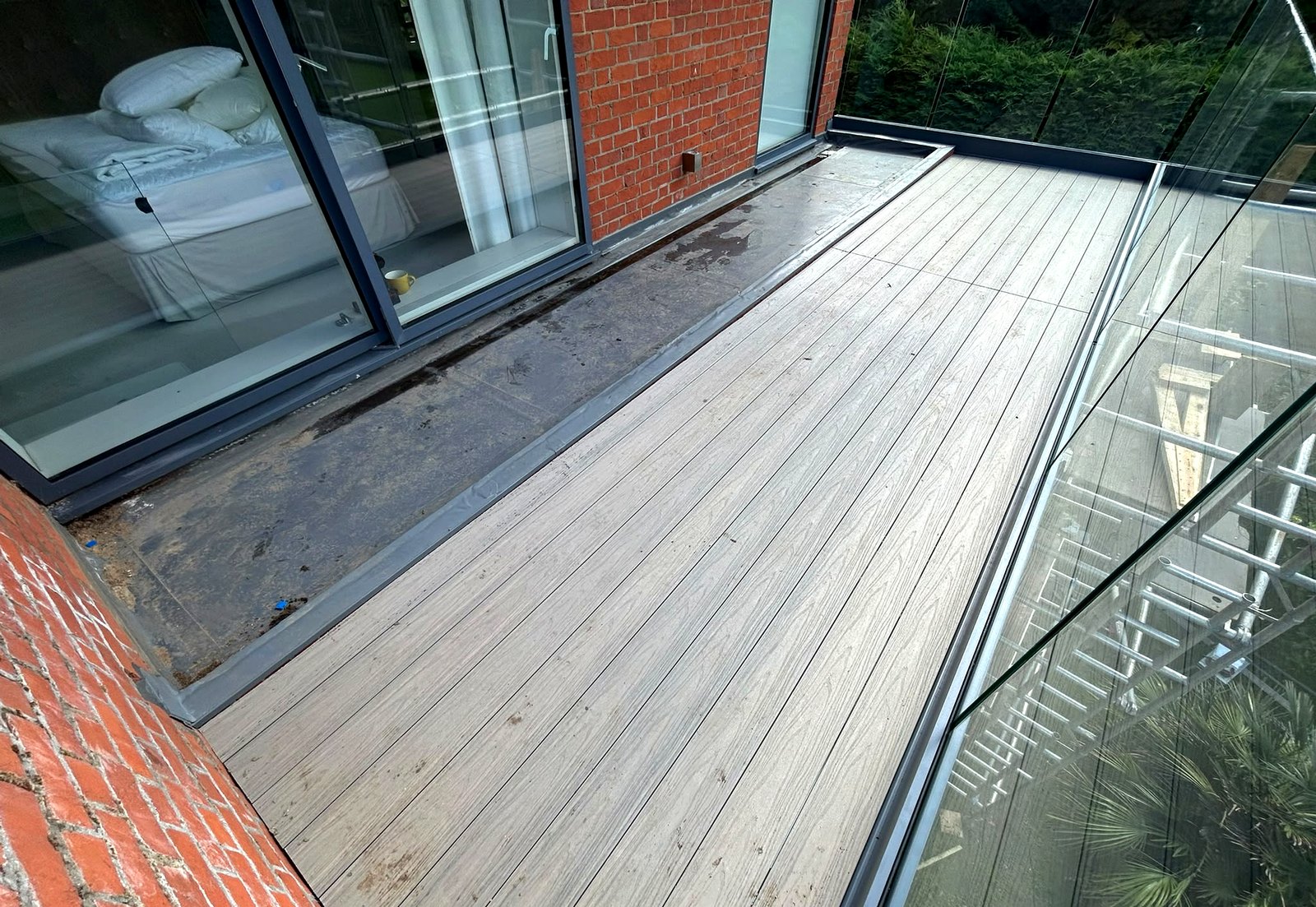 Walkout balcony with Antique composite decking and frameless glass balustrade, Bourne End, Buckinghamshire